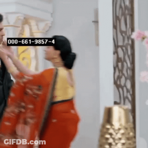 Woman In Red Saree Next To Man In Black Suit GIF