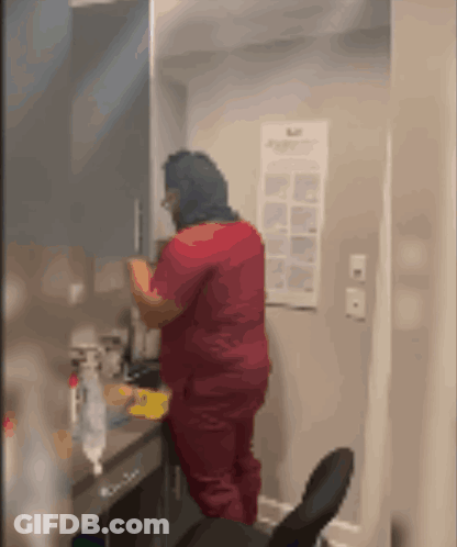 Woman In Red Scrub Top Standing In Front Of Mirror GIF