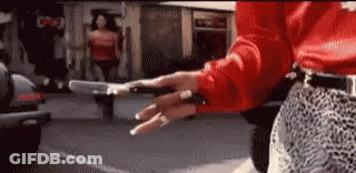 Woman In Red Shirt And Leopard Print Skirt Holding Gun GIF
