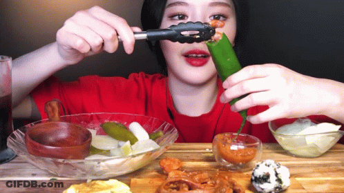 Woman In Red Shirt Eating Pickle With Tongs GIF
