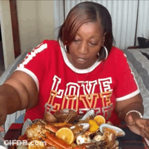 Woman In Red Shirt Saying Love Eating Seafood GIF