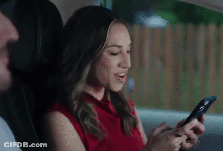 Woman In Red Shirt Sitting In Back Seat Looking At Phone GIF
