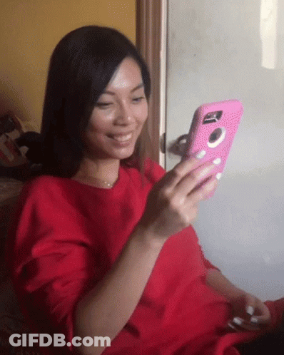 Woman In Red Shirt Smiling Holding Pink Phone GIF