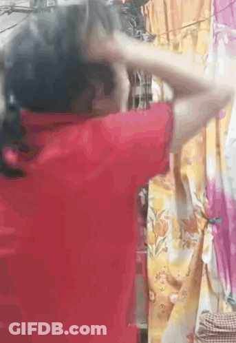Woman In Red Shirt Standing Before Curtain GIF