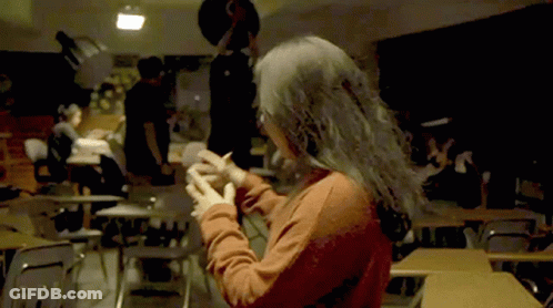 Woman In Red Shirt Standing In Classroom With Hands Folded GIF