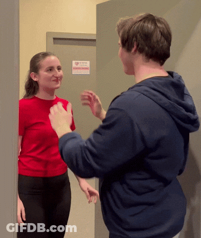 Woman In Red Shirt Talking To Man In Blue Hoodie GIF