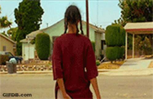 Woman In Red Shirt Walking Past House GIF