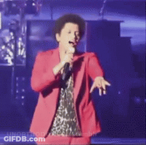 Woman In Red Suit Singing Into Microphone On Stage GIF