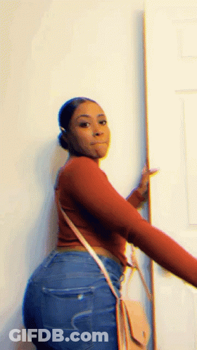 Woman In Red Sweater And Blue Jeans Standing Next To Door GIF