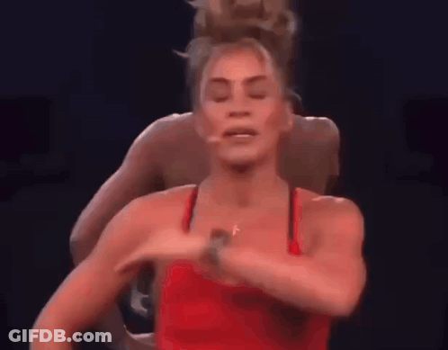 Woman In Red Tank Top Dancing On Stage With Man Behind GIF