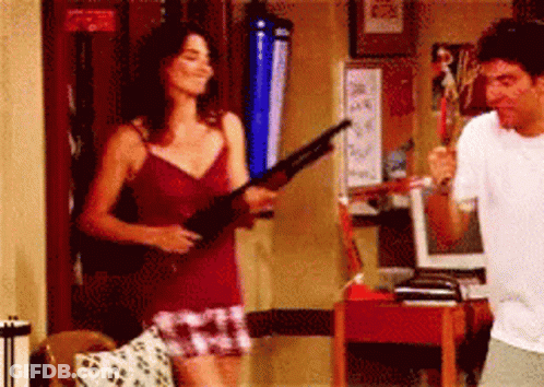 Woman In Red Tank Top Holding Shotgun Next To Man GIF
