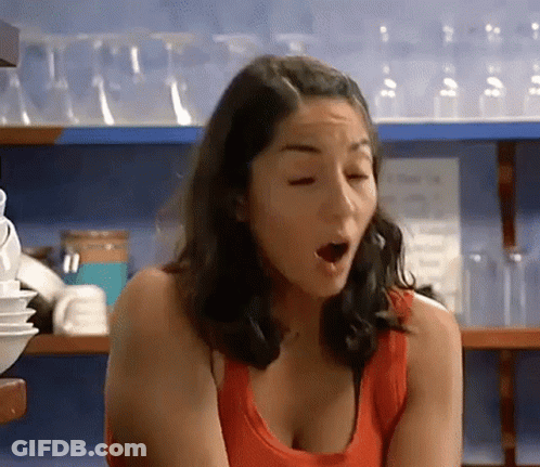 Woman In Red Tank Top Smiling In Front Of MTV Shelf GIF