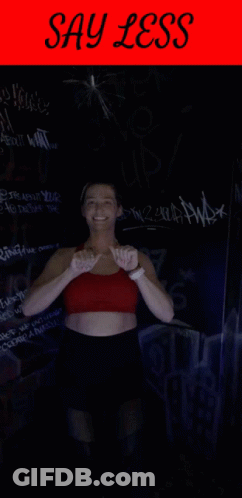 Woman In Red Top And Black Shorts With Say Less Sign GIF