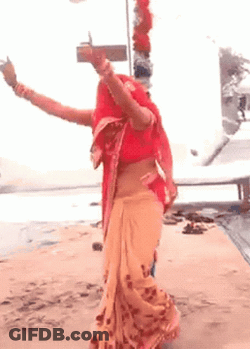 Woman In Red Top And Orange Skirt Dancing On Beach GIF