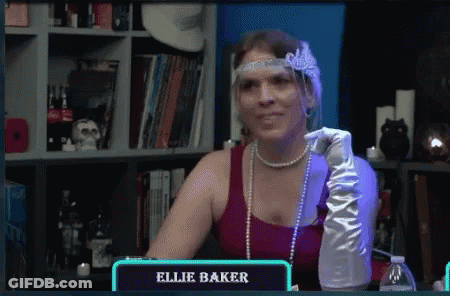 Woman In Red Top And White Gloves Sitting At Table Saying Ellie Baker GIF