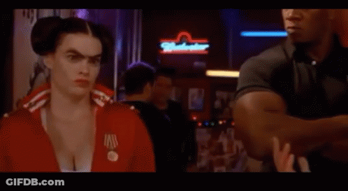 Woman In Red Uniform Smiling In Front Of Motel Sign GIF