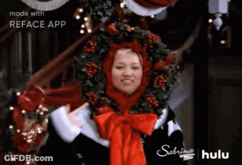 Woman In Santa Hat And Wreath With Christmas Tree GIF