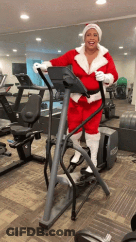 Woman In Santa Suit Riding Elliptical GIF