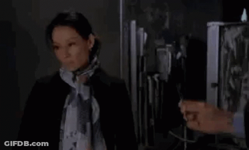 Woman In Scarf Standing Next To Man In Suit In Front Of Fridge GIF