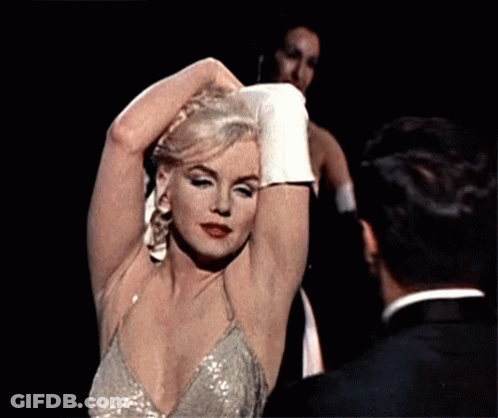Woman In Sequined Dress Adjusting Hair Next To Man In Tuxedo GIF