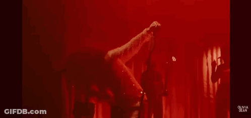Woman In Sheer Dress Singing Into Microphone On Stage GIF