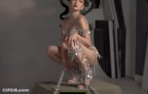 Woman In Short Dress Kneeling With Chains On Ankles GIF