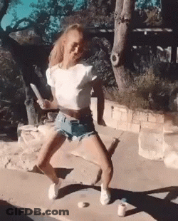 Woman In Shorts And White Crop Top Dancing On Sidewalk GIF