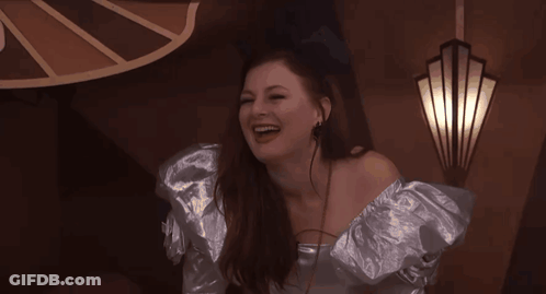 Woman In Silver Dress Laughing By Wall Light GIF