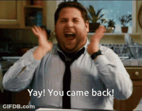Woman In Silver Dress Saying Welcome Back GIF