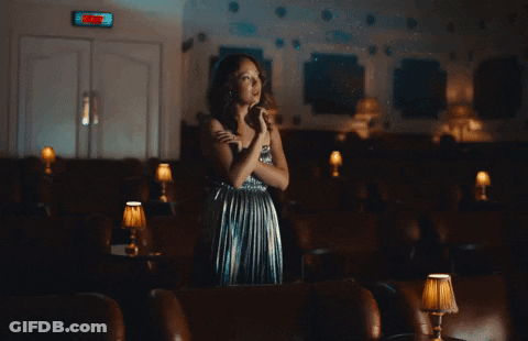 Woman In Silver Dress Under Exit Sign GIF