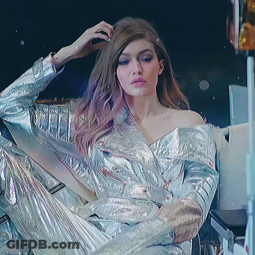 Woman In Silver Jacket And Pants Sitting GIF