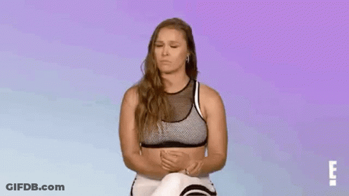Woman In Sports Bra And Leggings Sitting With Eyes Closed GIF