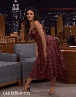 Woman In Strapless Dress Dancing In Front Of Chair GIF