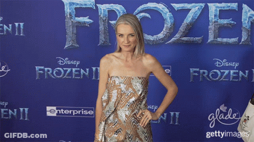 Woman In Strapless Dress In Front Of Blue Wall Saying Frozen II GIF