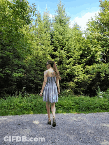 Woman In Striped Dress Walking Gravel Road GIF
