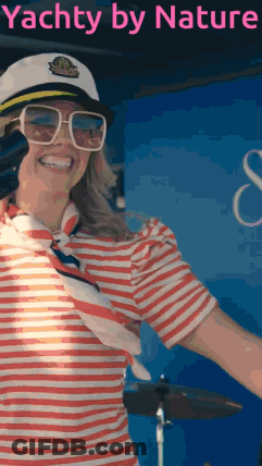 Woman In Striped Shirt And Captain Hat In Front Of Yacht By Nature Sign GIF