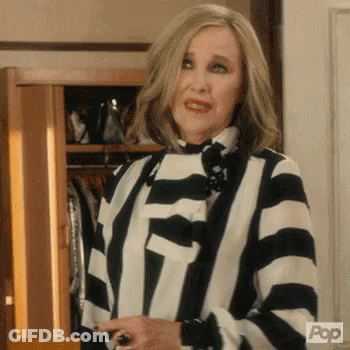 Woman In Striped Shirt Holding Wine In Front Of Closet GIF