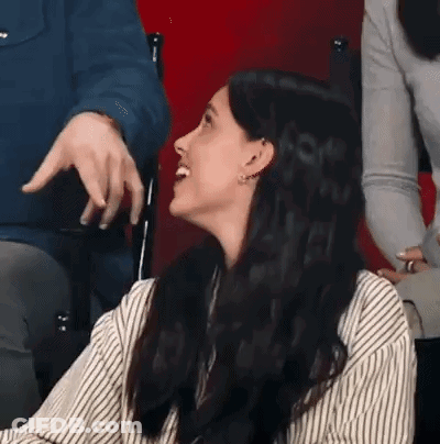 Woman In Striped Shirt Laughing While Man Points GIF