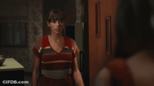 Woman In Striped Shirt Saying Hi In Dark Room GIF