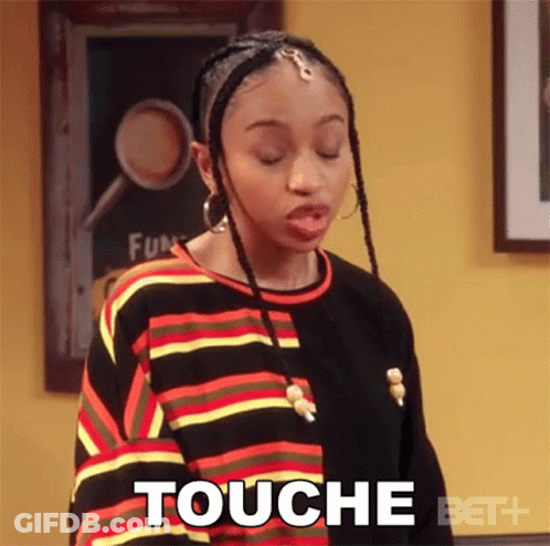 Woman In Striped Shirt Saying Touché In Front Of Yellow Wall GIF