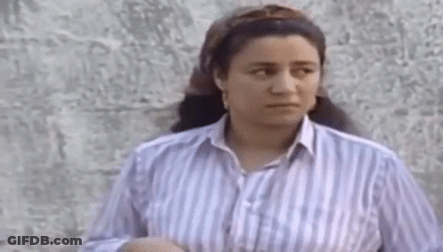 Woman In Striped Shirt Standing By Wall GIF