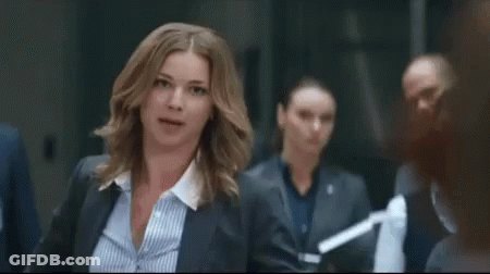 Woman In Suit And Striped Shirt Standing In Room GIF