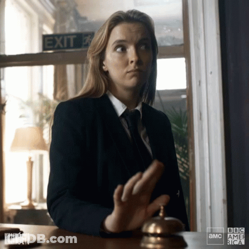 Woman In Suit And Tie At Desk With Exit Sign GIF