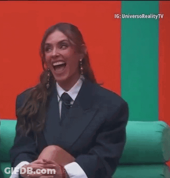 Woman In Suit And Tie Laughing On Couch GIF