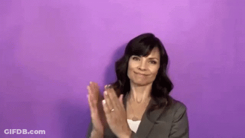 Woman In Suit Clapping In Front Of Purple Wall GIF