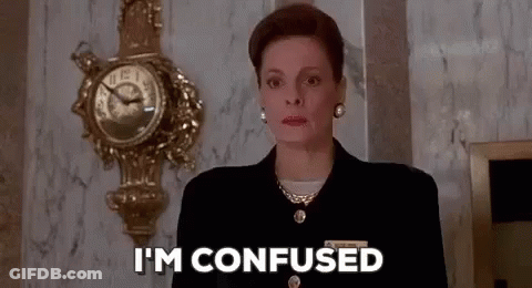 Woman In Suit Confused In Front Of Clock GIF