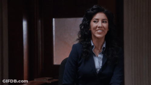 Woman In Suit Smiling In Dark Room GIF