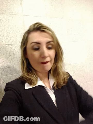Woman In Suit Standing Before Tiled Wall GIF