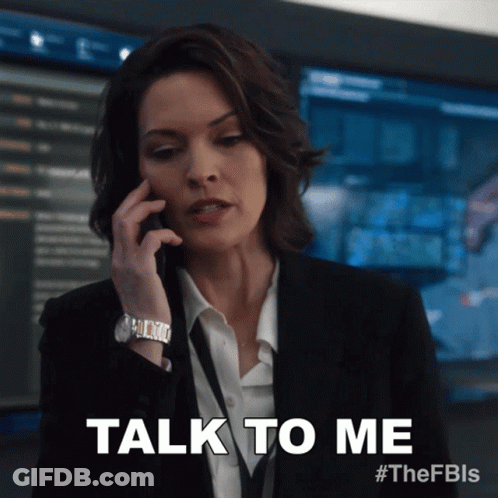 Woman In Suit Talking On Phone Saying Talk To Me GIF