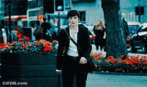 Woman In Suit Walking Down Street With Flowers GIF